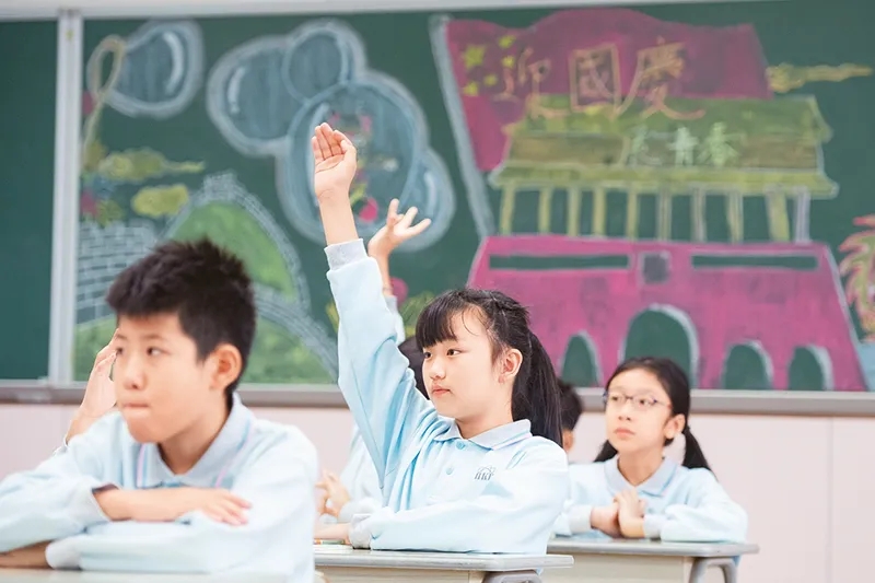 澳门中小学学生使用的教材《品德与公民》中有丰富的关于国情、国旗、国歌的内容,学生们可以从中学到很多关于祖国的知识,培养对祖国和澳门的感情。图为2019年11月25日,澳门濠江中学附属英才学校的学生在课堂上举手回答老师提问。 新华社记者 张金加/摄